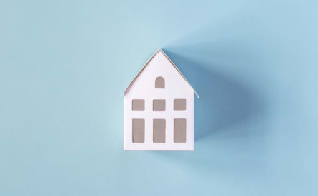 Photo of a white house model on a blue background.